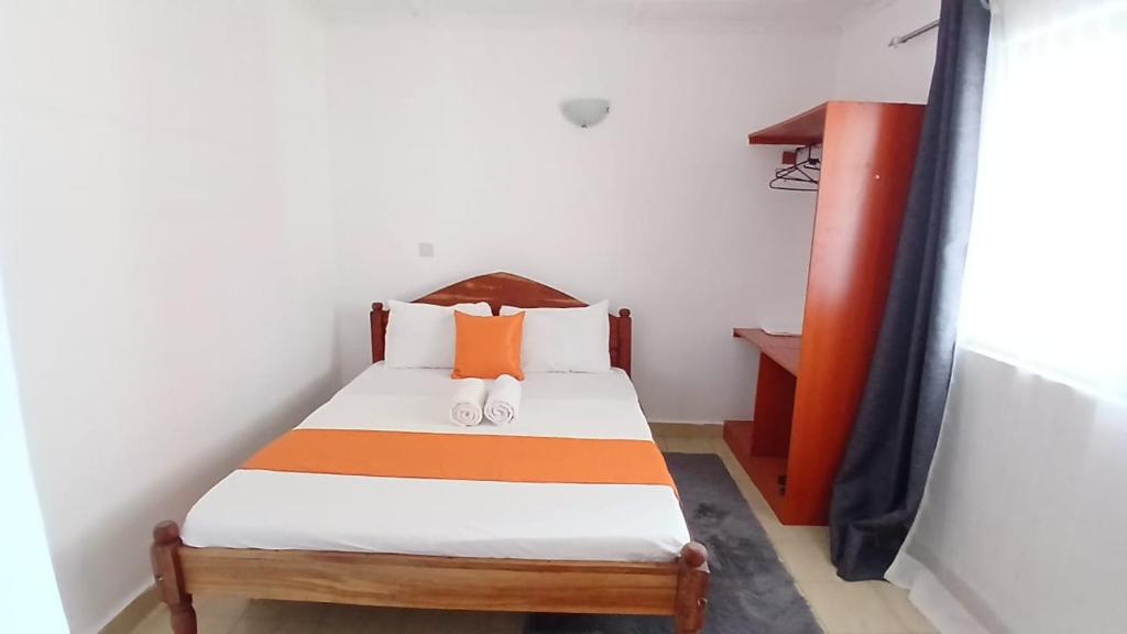 una piccola camera da letto con un letto e una scrivania di Treasured Haven Stay a Ukunda