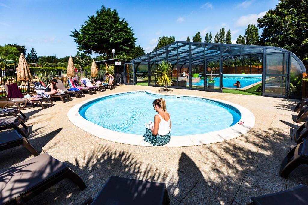 a woman sitting in front of a swimming pool at Glamping Terre & Mer in Étables-sur-Mer