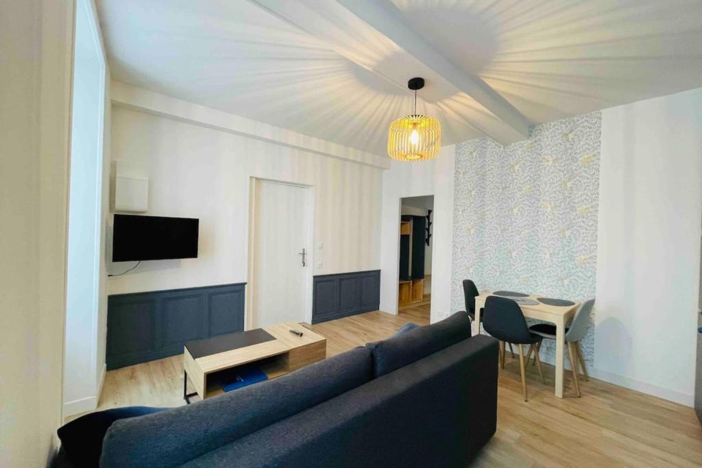 a living room with a blue couch and a table at Bel appartement avec cour privée in Saint-Jean-dʼAngély