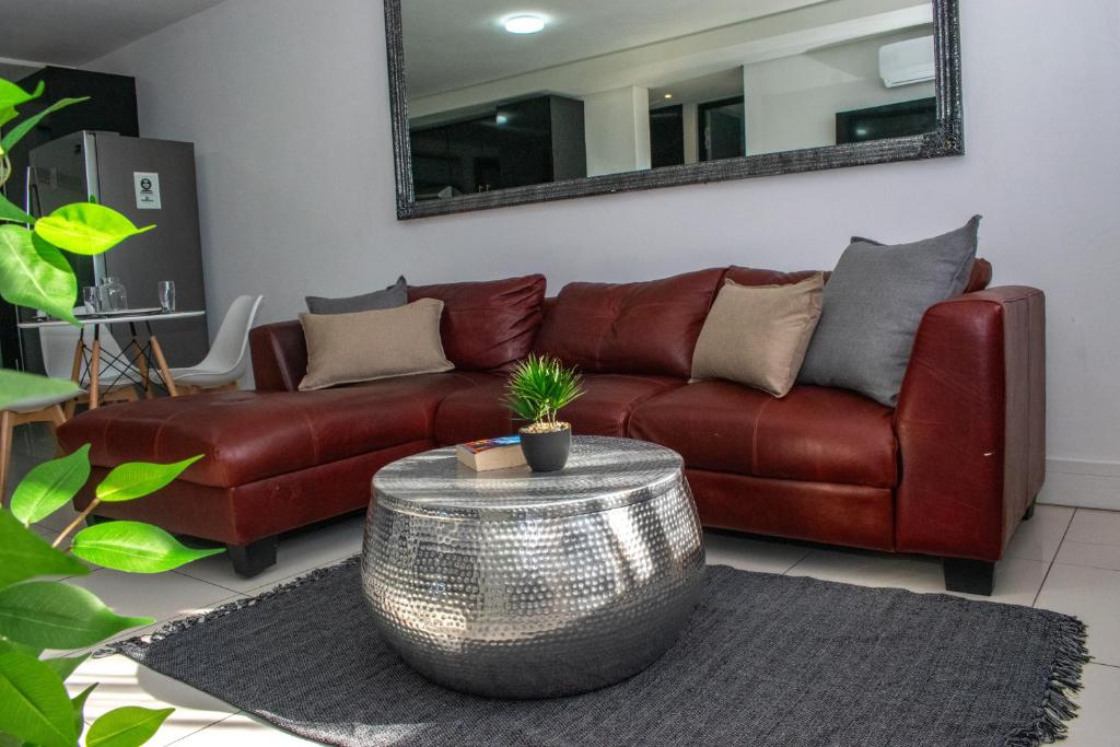 Una sala de estar con un sofá de cuero marrón y una mesa. en Twilight Self Catering, en Windhoek