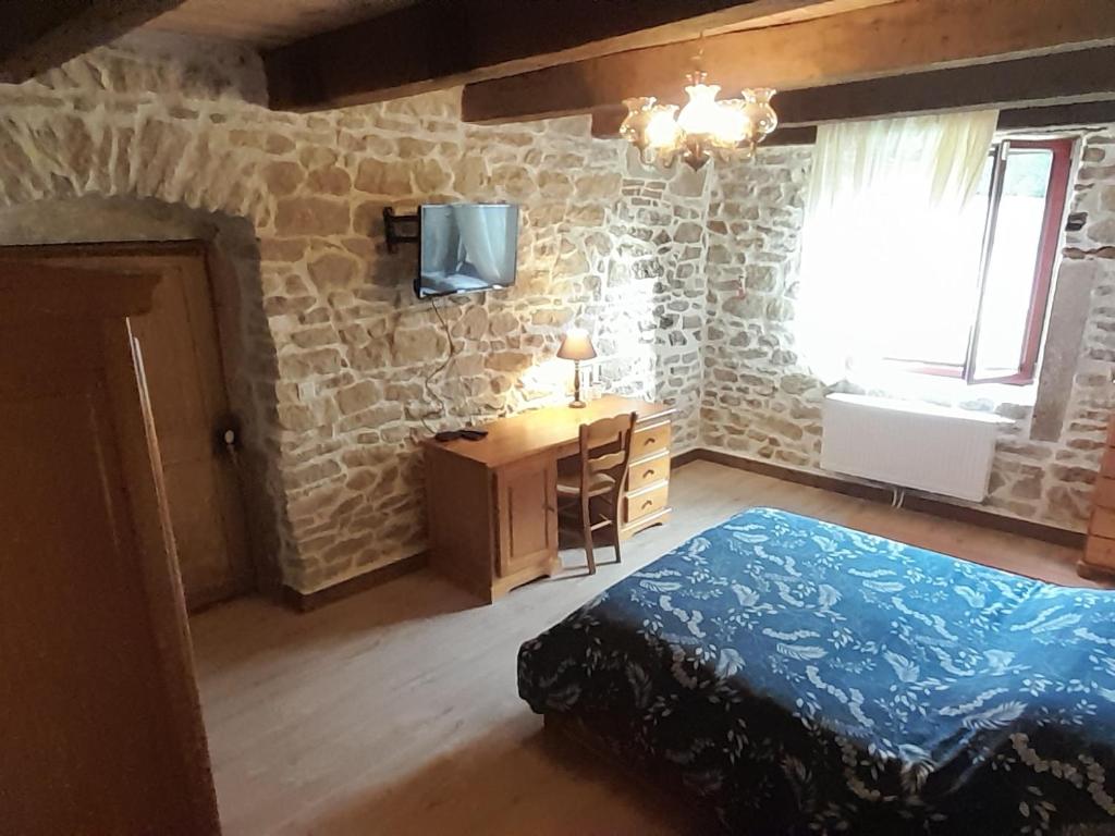 a bedroom with a bed and a tv on a stone wall at Chambre double chez Emilienne in Téterchen