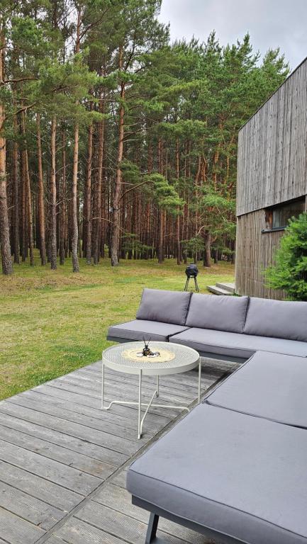 eine Terrasse mit einem Sofa und einem Couchtisch in der Unterkunft Vila MurMur Papėje in Pape
