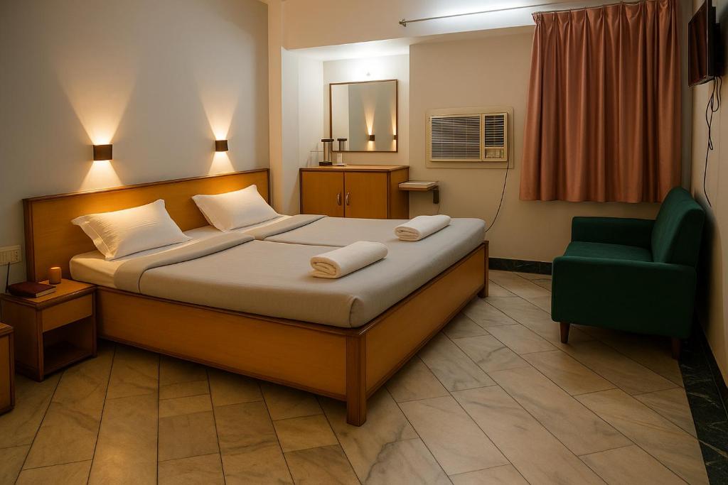 a hotel room with a bed and a green chair at Subhash Hotel in Prayagraj