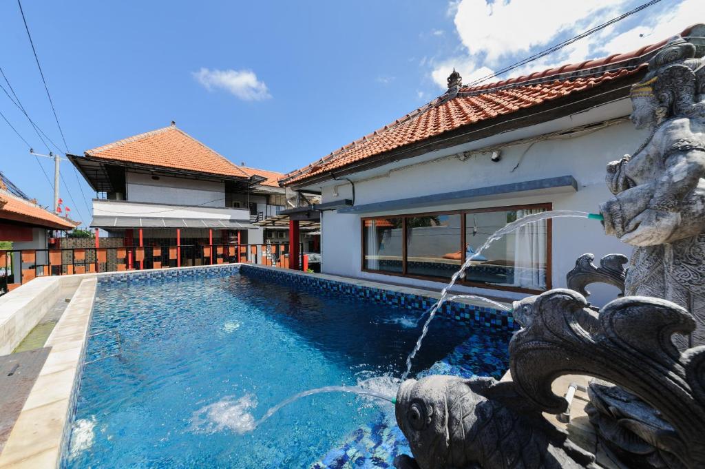 a pool with a water fountain in front of a house at Urbanview Ava Guest House Goa Gong in Jimbaran