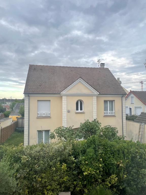 a yellow house with a brown roof at Séjour à Paris in Bezons