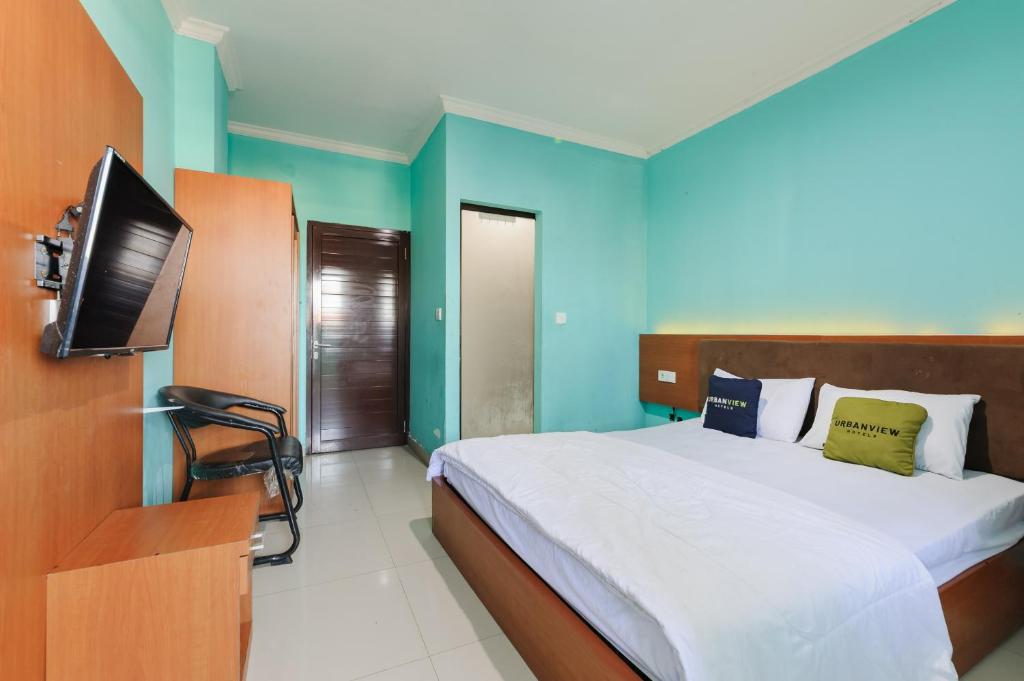 a bedroom with a bed and a flat screen tv at Gita Inn Bali RedPartner in Denpasar