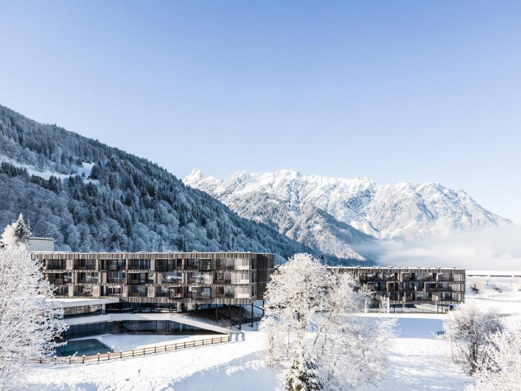 施伦斯Falkensteiner Family Hotel Montafon - The Leading Hotels of the World的雪地里的酒店，背景是群山