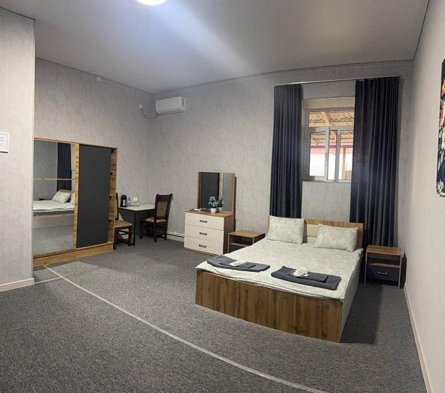 a bedroom with a bed and a desk and a table at Osiyo in Olmaliq