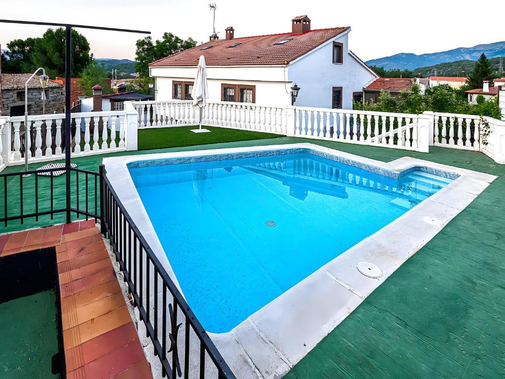 una piscina con valla y una casa en Casa Viria, en Navaluenga