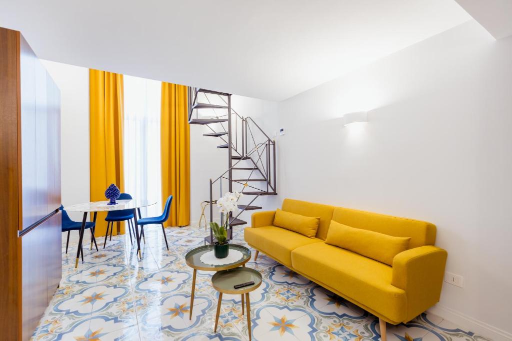 a living room with a yellow couch and a table at Atri Rooms Centro Storico Napoli in Naples