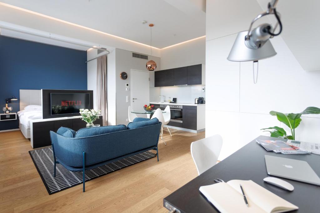 a living room with a blue couch and a kitchen at Skyline City Loft in Vienna