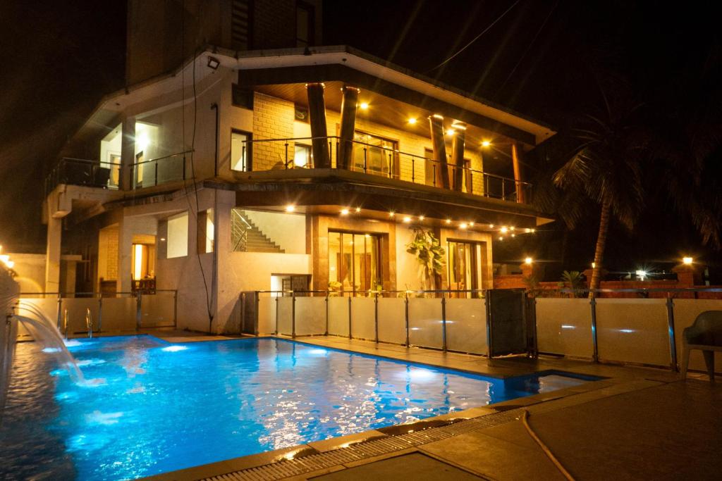 a swimming pool in front of a house at night at Coral Bay Villa in Kashid