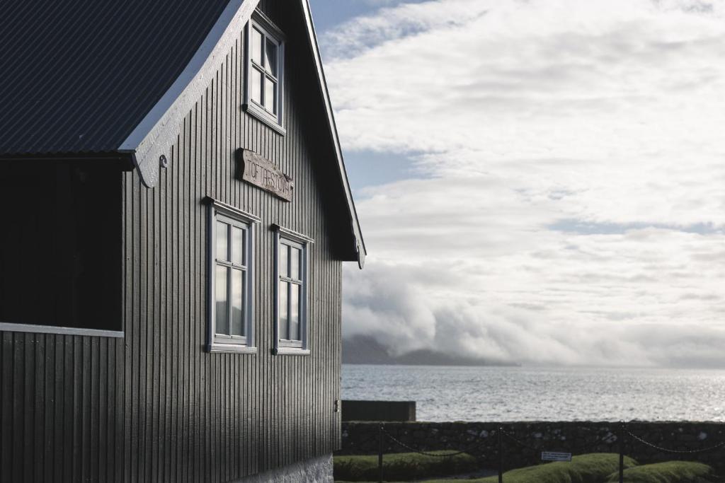 un edificio con dos ventanas junto al océano en Toftarstova - Seaview - Historic - 3BR House, en Kvívík