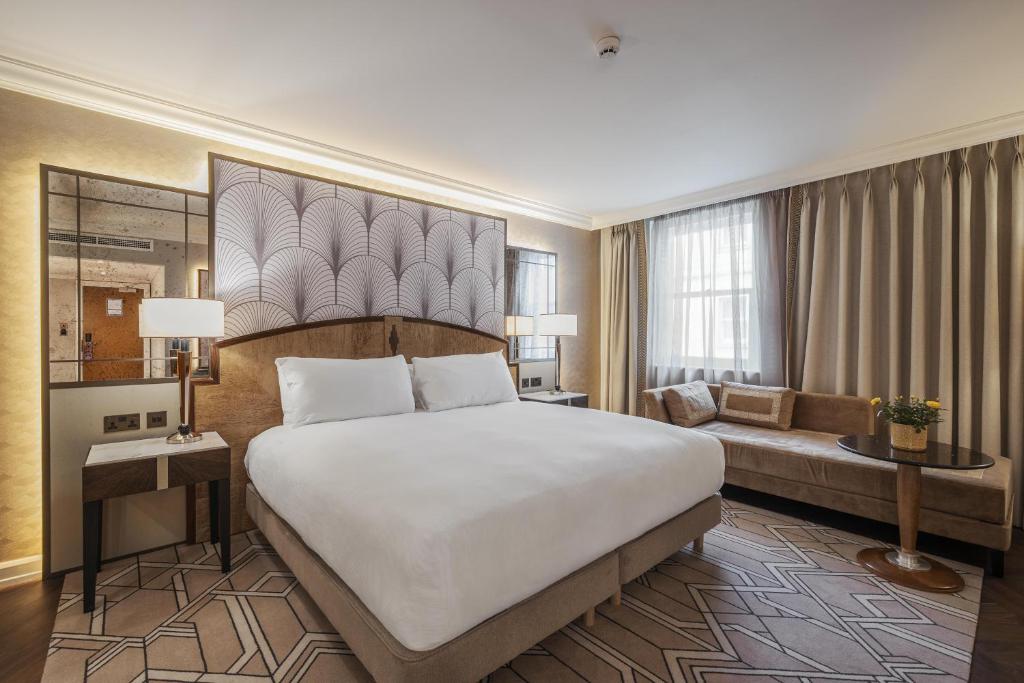 ロンドンにあるヒルトン ロンドン パディントンの大きなベッドとソファのあるホテルの部屋