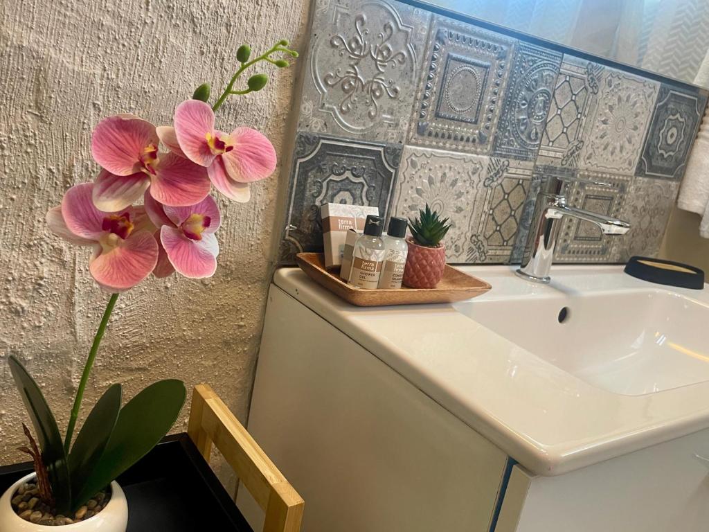 a bathroom with a sink and flowers on a counter at 42 On Fraser in Howick