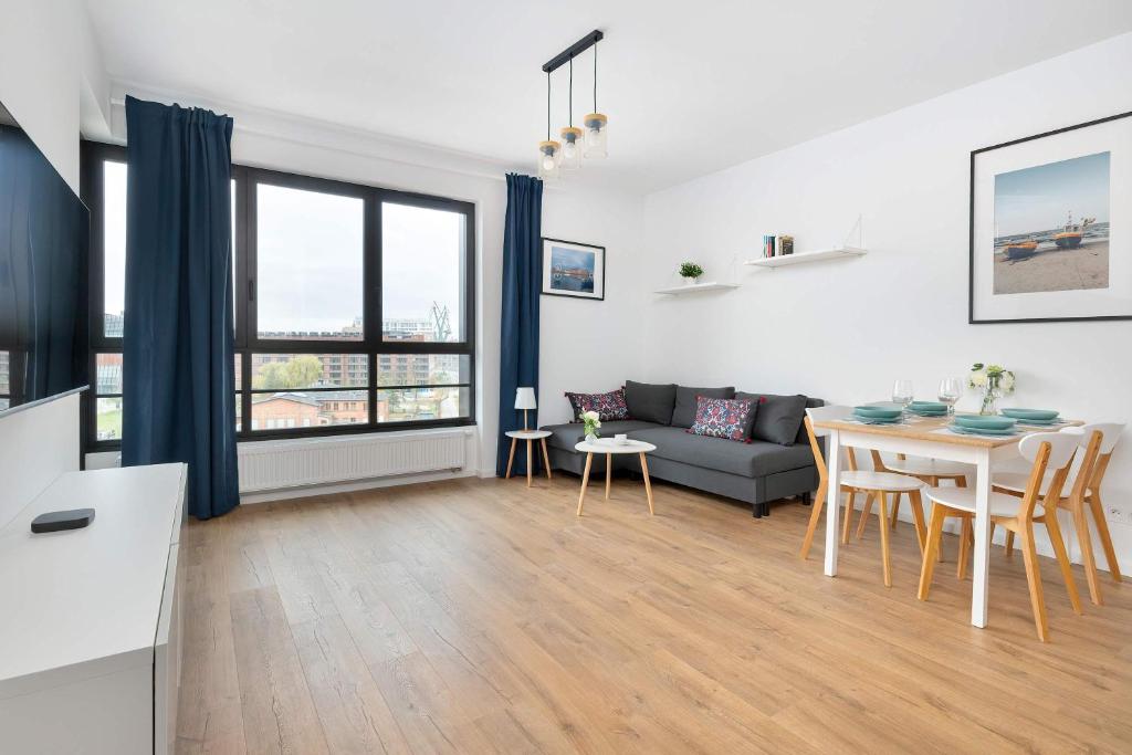 een woonkamer met een tafel en een bank bij Modern Apartment with Historic Shipyard Views and Parking by Noclegi Renters in Suchanino