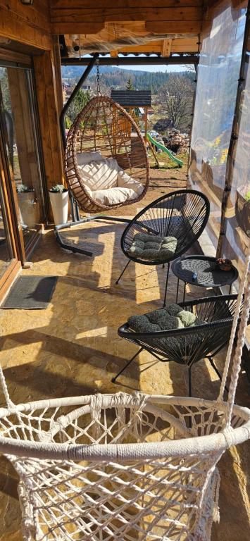 deux chaises en osier et des balancelles sur une véranda dans l'établissement Brvnara “Vidik Breg”, à Sekulić 