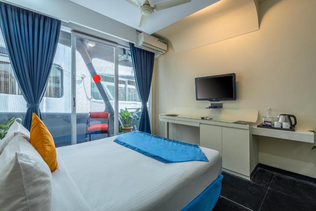 a bedroom with a bed with a tv and a window at Afallon Hotels in Bangalore