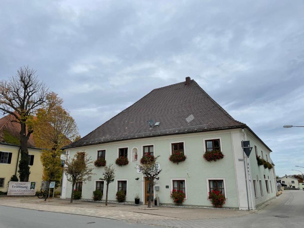 ein weißes Gebäude mit braunem Dach an einer Straße in der Unterkunft Zum Posthalter in Hemau