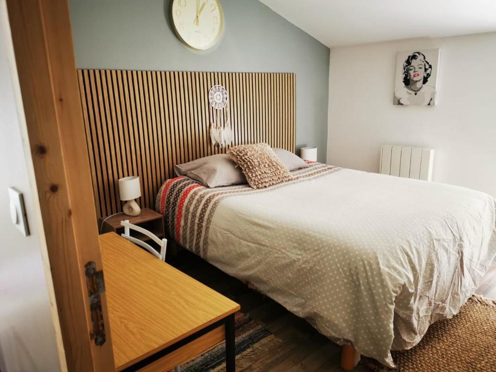 een slaapkamer met een bed en een klok aan de muur bij Studio - Chez Ana et Jonathan in Chantonnay