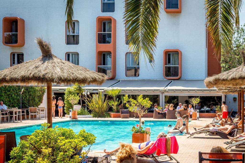 a group of people sitting around a pool at a hotel at Hotel Aquarius in Canet-en-Roussillon