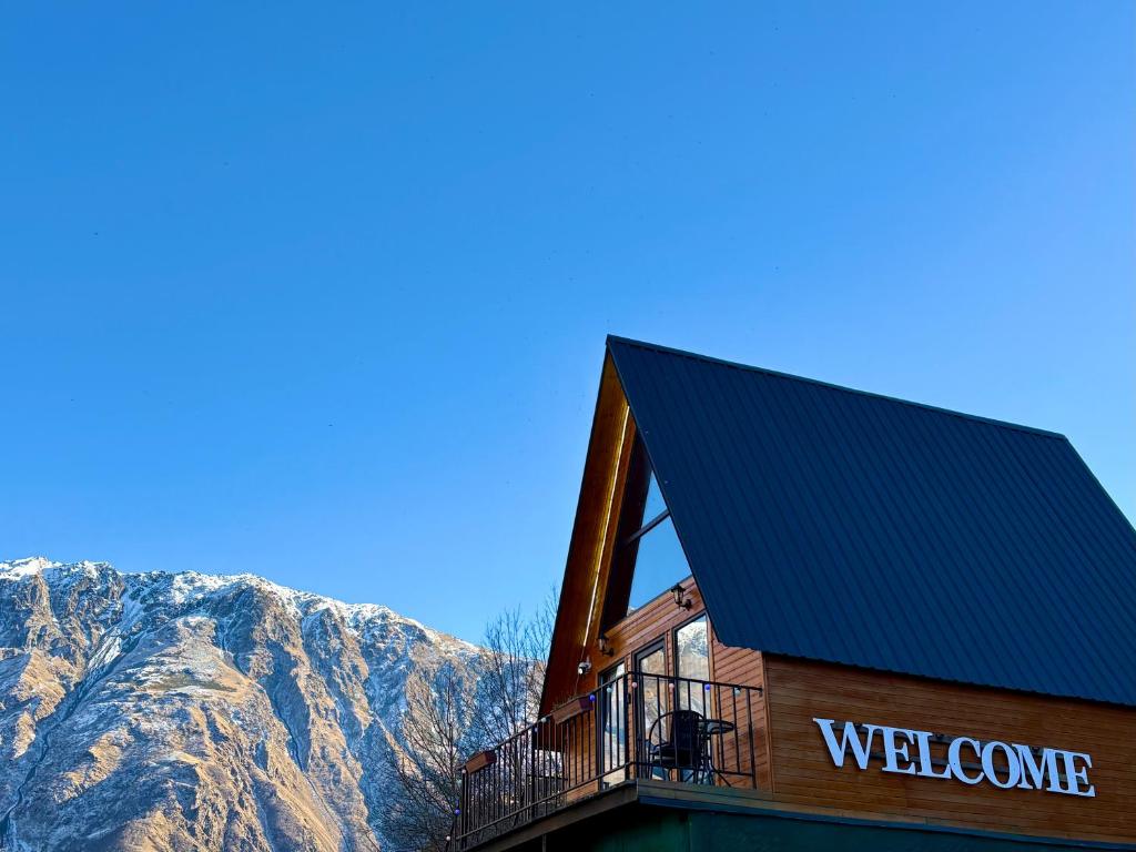a building with a balcony with mountains in the background at Welcome Cottage in Kazbegi