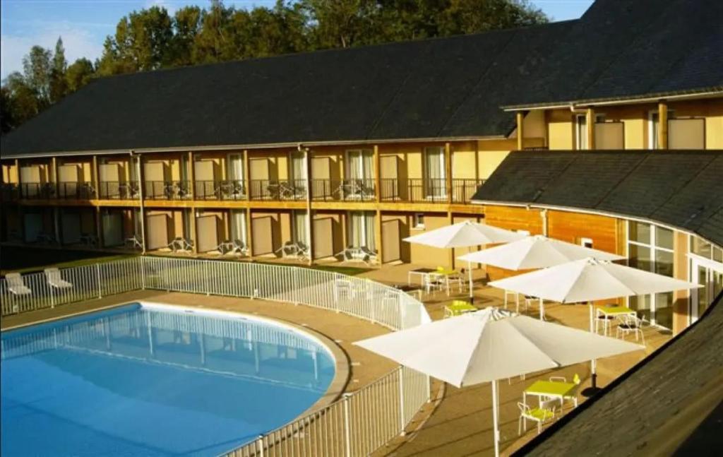 a hotel with a swimming pool and umbrellas at Appartement convivial à Équemauville de 36 m² avec jardin in Équemauville