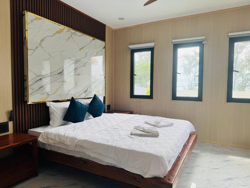 Un dormitorio con una gran cama blanca con almohadas azules. en Real Koh Rong, en Kaôh Rŭng (3)