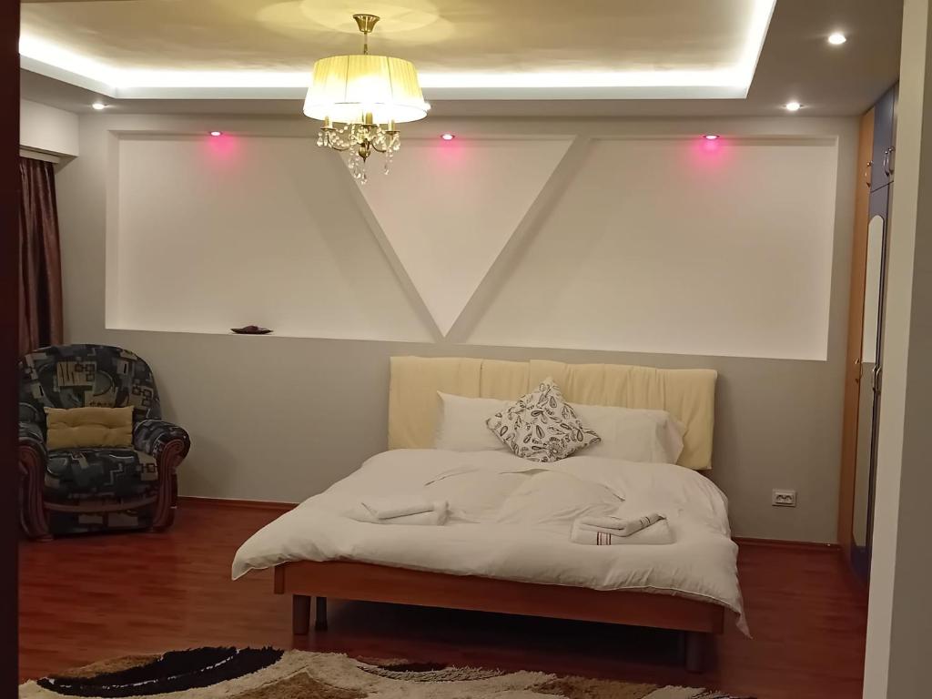 a bedroom with a white bed with a chandelier and a chair at Elixir studio in Bucharest