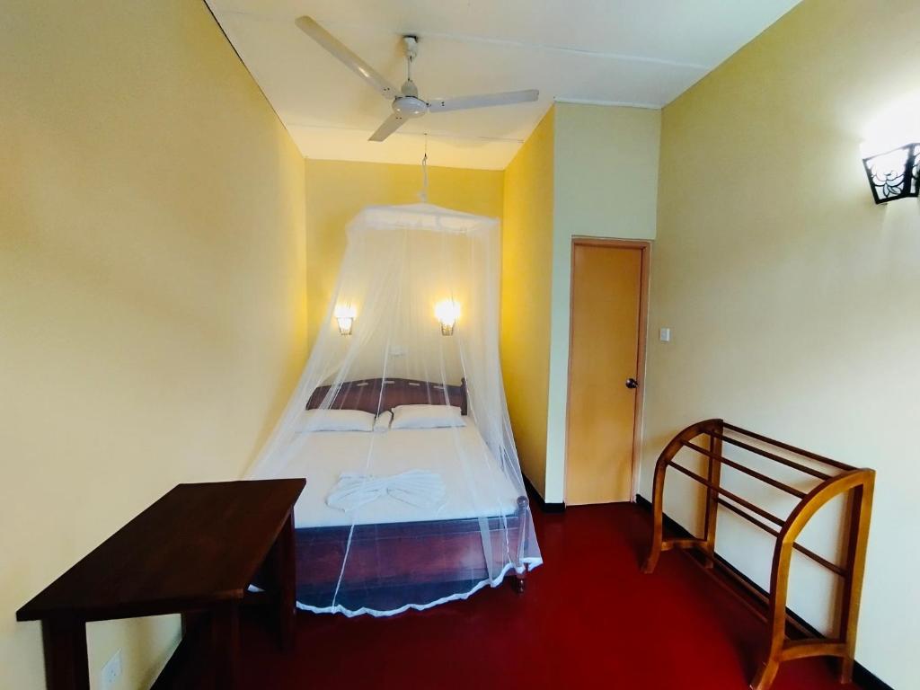 a bedroom with a bed with a mosquito net at Why Not Guest house in Hikkaduwa