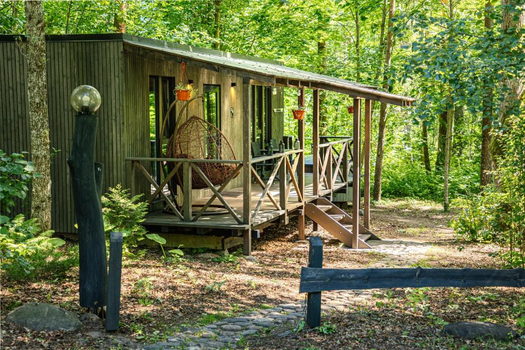 Cabaña verde pequeña con porche en el bosque en Meža māja, en Zaķumuiža