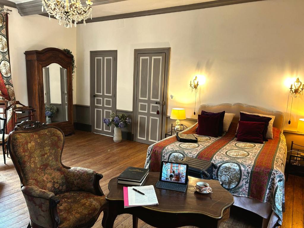 a bedroom with a bed and a table and a chair at Séjour romantique ou professionnel au Château isigny, Charme et feu de cheminée in Isigny-le-Buat