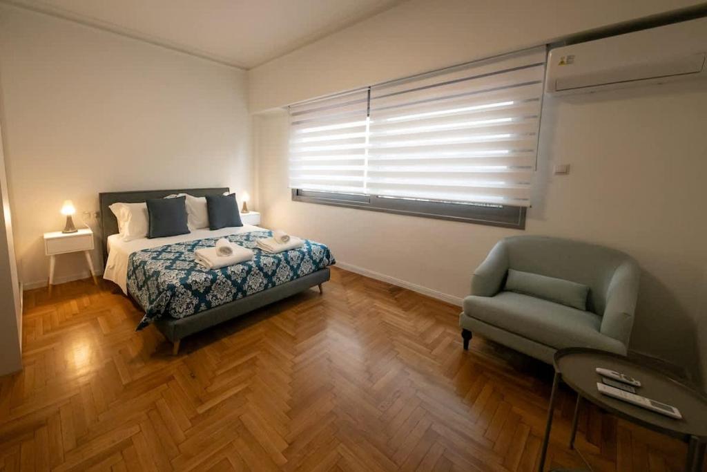 a bedroom with a bed and a chair and a window at Comfy 2BR Flat in Central Athens in Athens