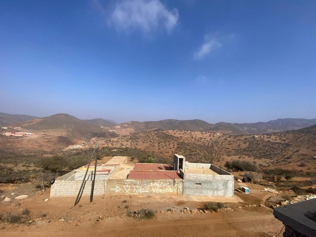 een gebouw in de woestijn met bergen op de achtergrond bij house surrounded by trees in a village in Tiznit