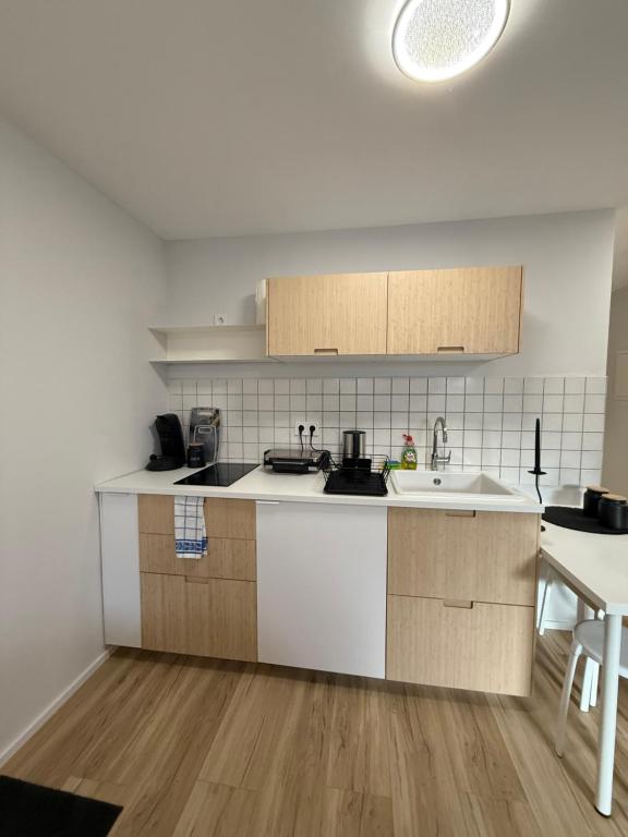 Una cocina con gabinetes blancos y un fregadero y una mesa. en Cozy Room - Self Check In - Bad Nauheim, en Bad Nauheim