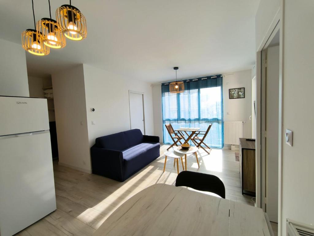 a living room with a blue couch and a table at Elégante Océan - Terrasse vue mer - Hyper centre in Saint-Brévin-lʼOcéan