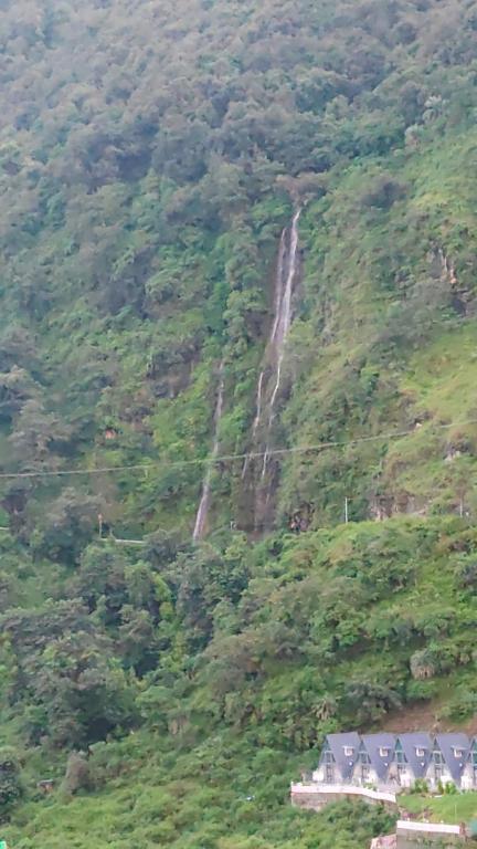 ein Wasserfall an der Seite eines Berges mit Häusern in der Unterkunft streem View in Masuri