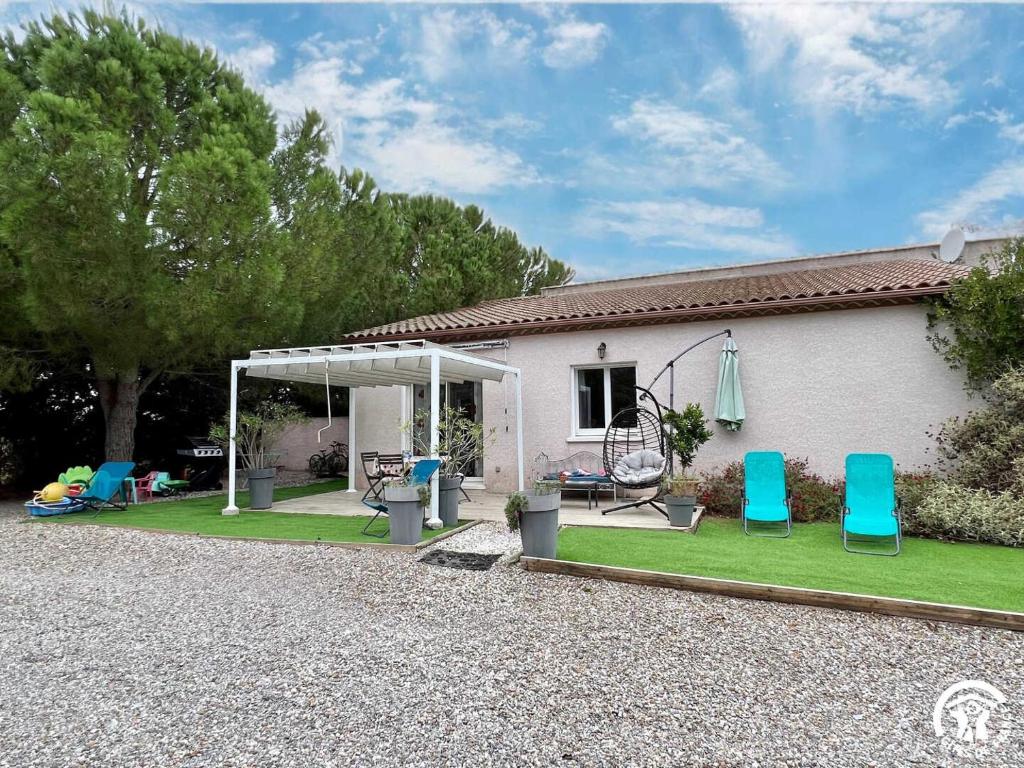 a house with a yard with two blue chairs at Le gite du pech de saint jean in La Redorte