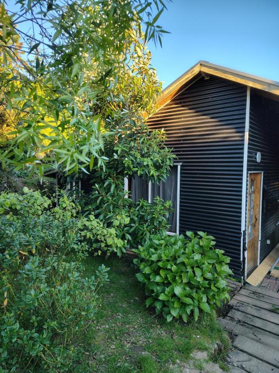 Una casa con un montón de plantas delante de ella. en Departamento Refugio Compinches, Castro Chiloé, en Tentén