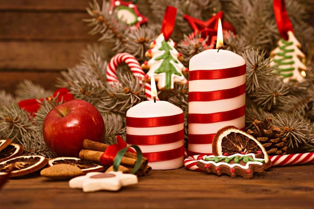 Rambaldi Apartments Casa nr 5 في باردولينو: شمعتان حمراء وبيضاء وزينة عيد الميلاد على الطاولة