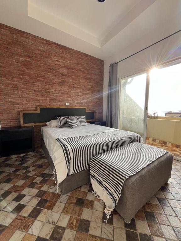 Un dormitorio con dos camas y una pared de ladrillo. en Ims'Chill Hotel, en Imsouane