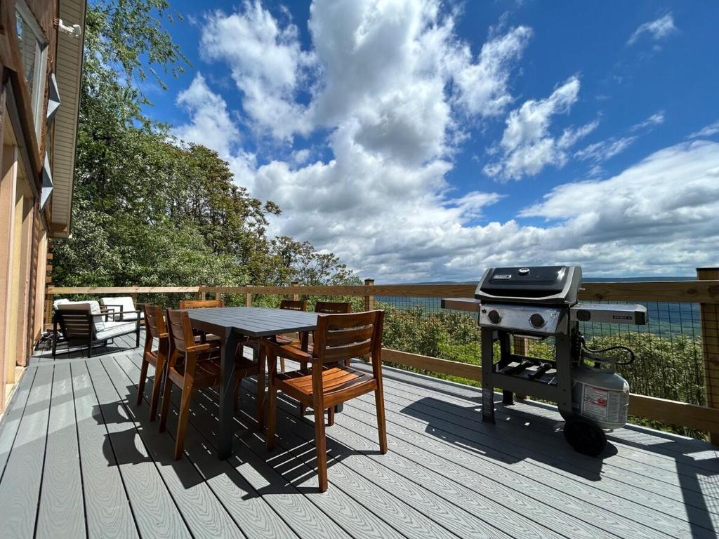 a grill and a table and chairs on a deck at Modern Mountaintop Cabin with a gorgeous view in Great Cacapon
