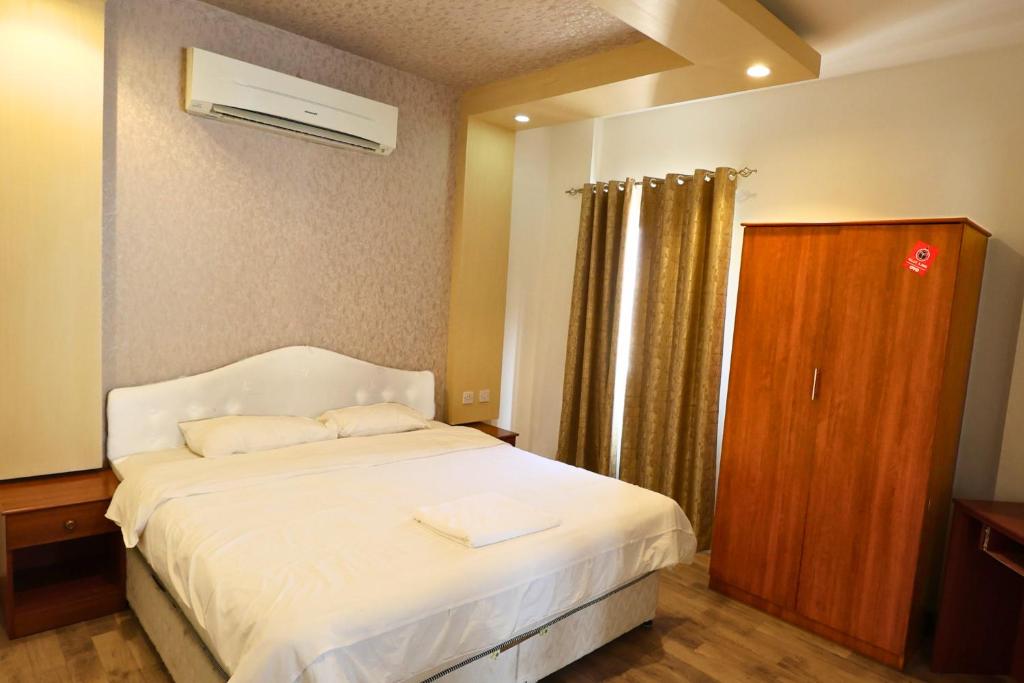 a bedroom with a white bed and a wooden cabinet at Muscat-Seeb 1BHK comfort apartment in Seeb