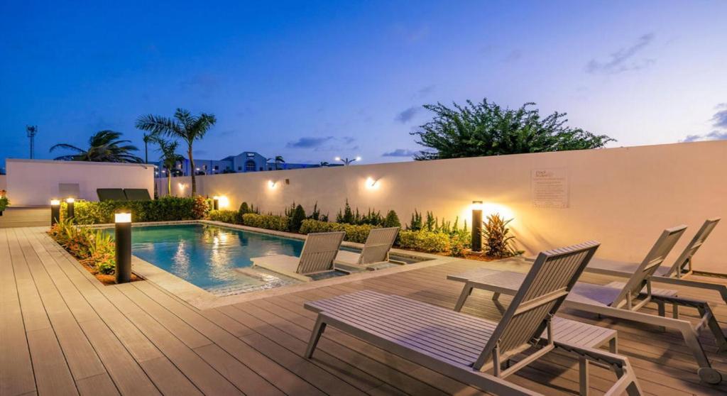 een patio met stoelen en 's avonds een zwembad bij 2BR2BA Condo w/ Pool & Gym – Walk to Palm Beach! in Palm-Eagle Beach