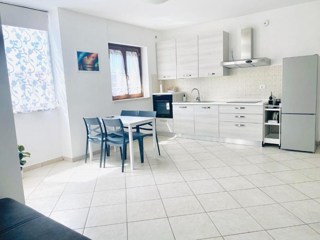 a kitchen with white cabinets and a table and chairs at Fele's house in Guidonia