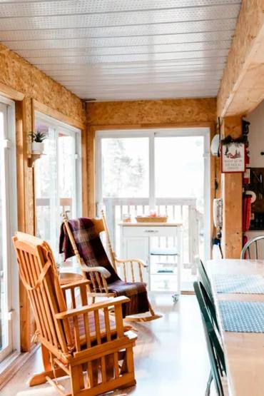 een kamer met schommelstoelen, een tafel en ramen bij Chalet Le Mona in Notre-Dame-Des-Bois
