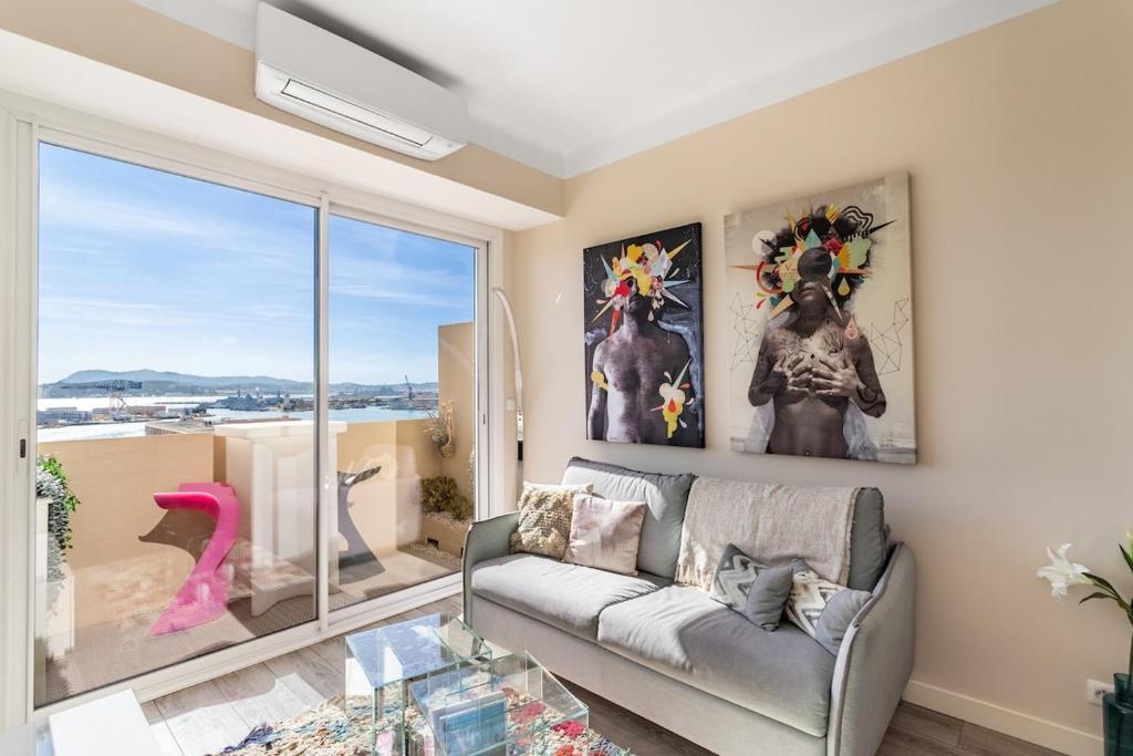 a living room with a couch and a large window at Splendide appartement climatisé vue mer in Toulon