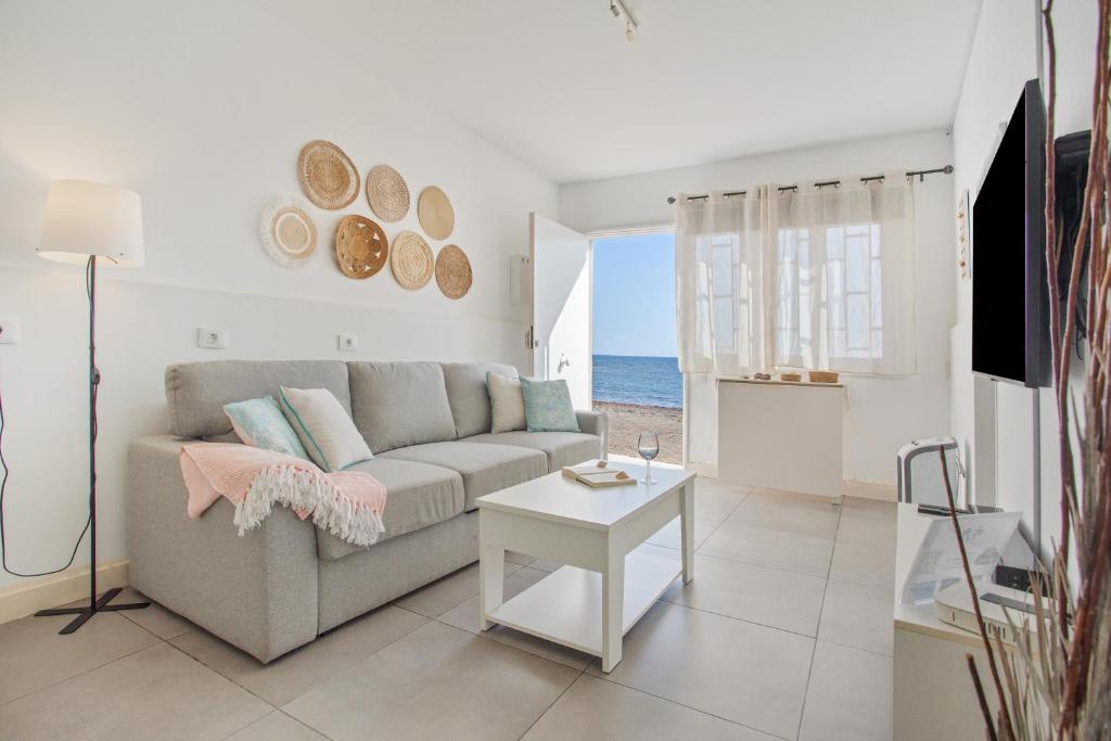 ein Wohnzimmer mit Sofa und Tisch in der Unterkunft La Casita De La Playa in Puerto de las Lajas