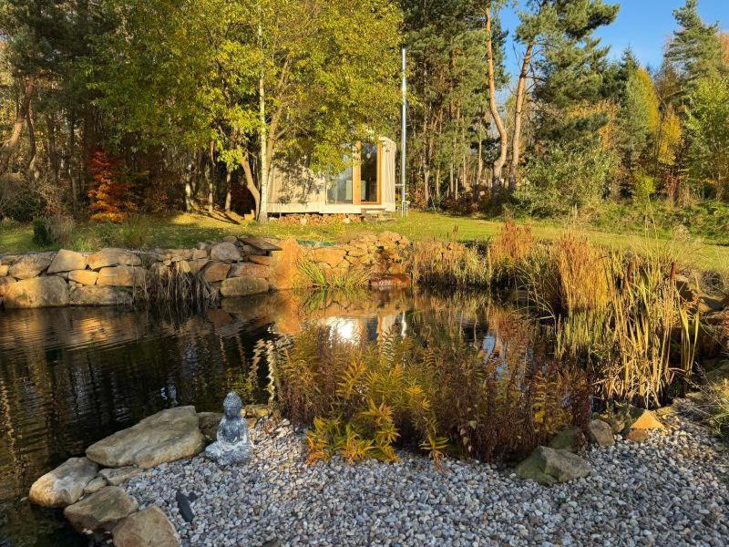 a pond with a house in the background at Malá jurta na Souvrati in Mostek
