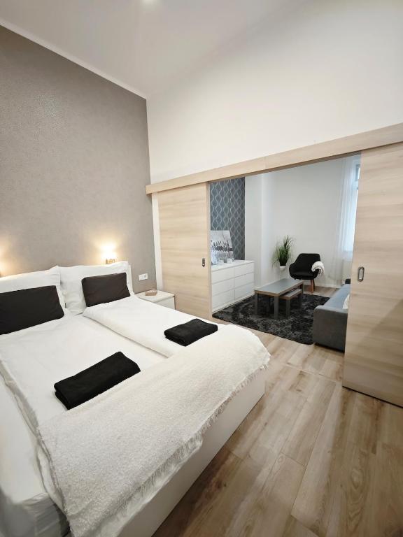 a bedroom with a large white bed and a living room at Vibe City Apartment in Kecskemét